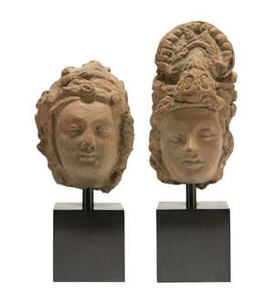 RTOTwo Gandharan red sandstone heads, reworked in areas, 3-4th century AD, depicted wearing headdresses, each mounted on a plinth, 15cm. and 10.5cm. high (with