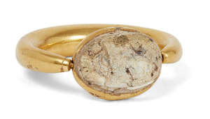 
	
		A gold ring with scarab setting, the thick rounded gold band tapering at the bezel,...