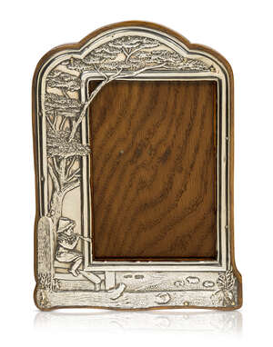 An Edwardian silver and oak photograph frame
		Partial maker's mark W & SNS, London hallmarks 1904
		The silver decorated with a boy playing a pipe, sitt